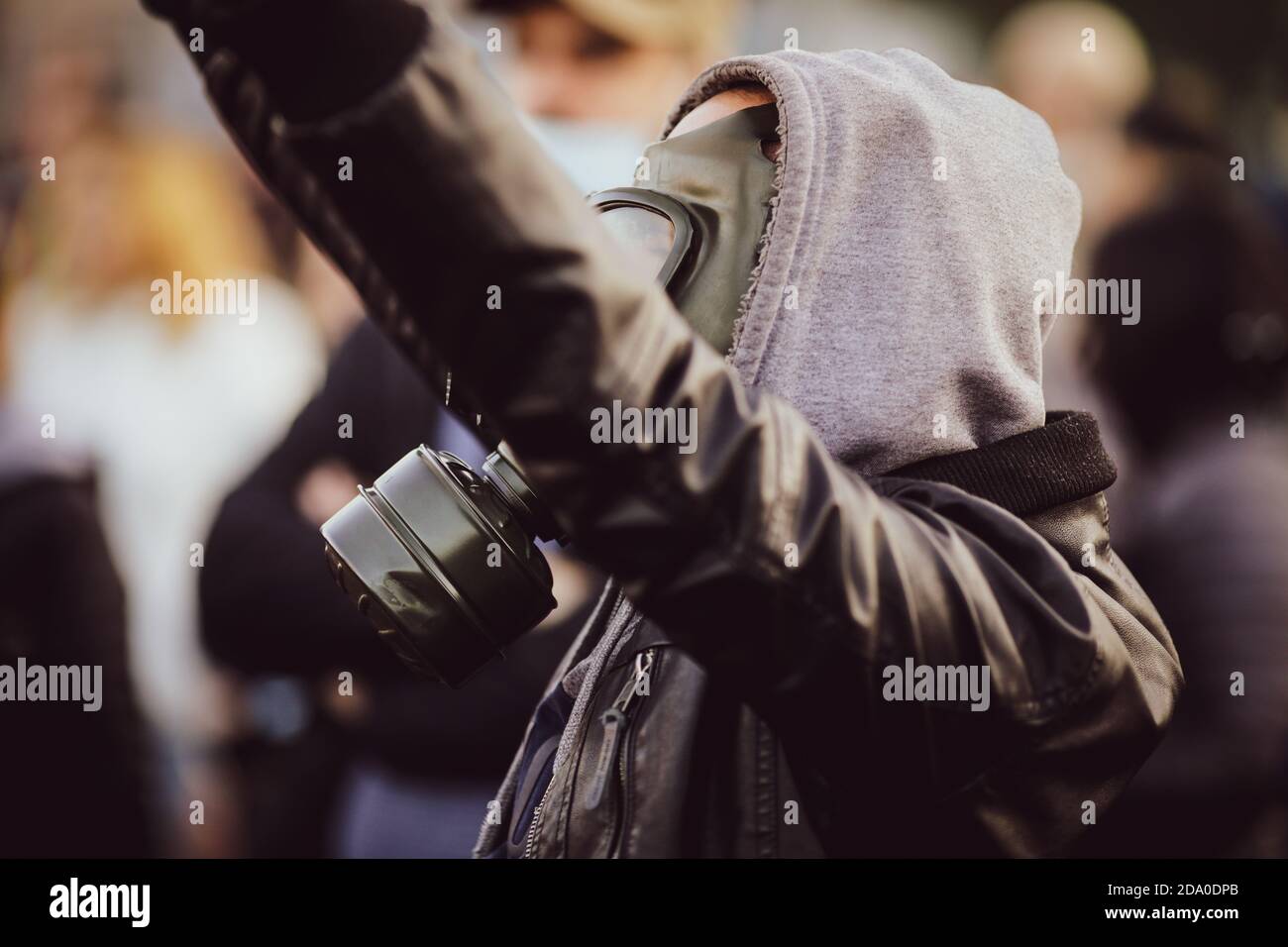 Shallow depth of field (selective focus) image with a protestor wearing a hoodie and a military gas mask. Stock Photo