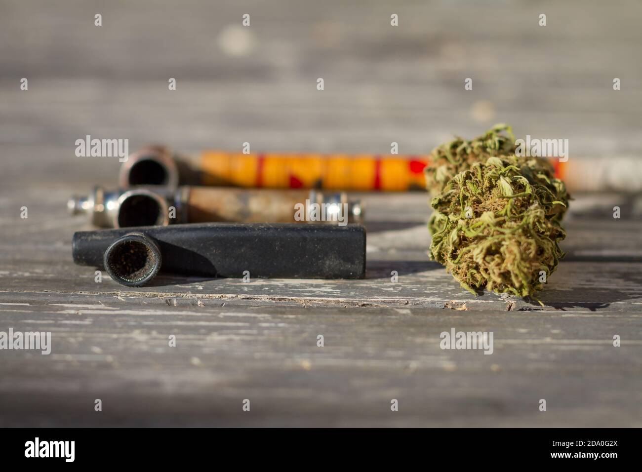 Marijuana bud with smoking pipes in the background. Stock Photo