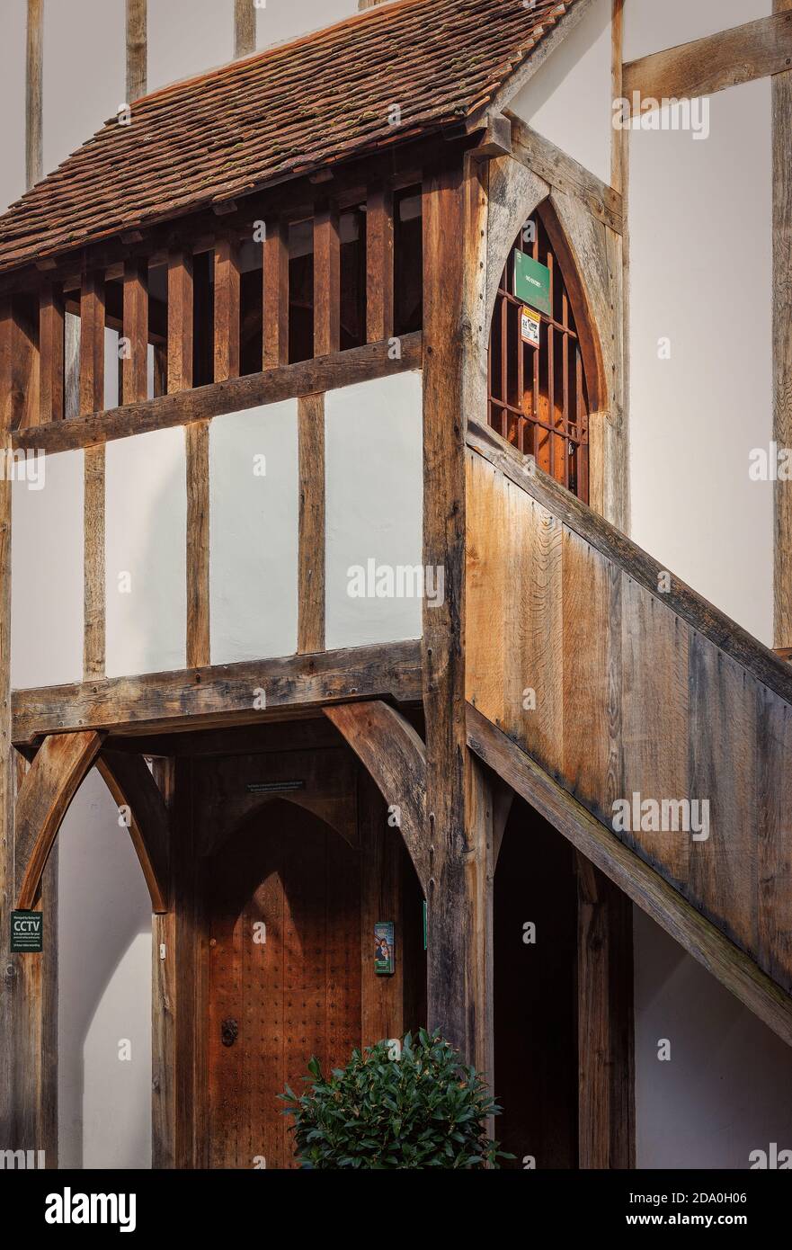 An historic half-timbered building. A door sits under a gallery and a stairway runs up the side to an iron gate. Stock Photo