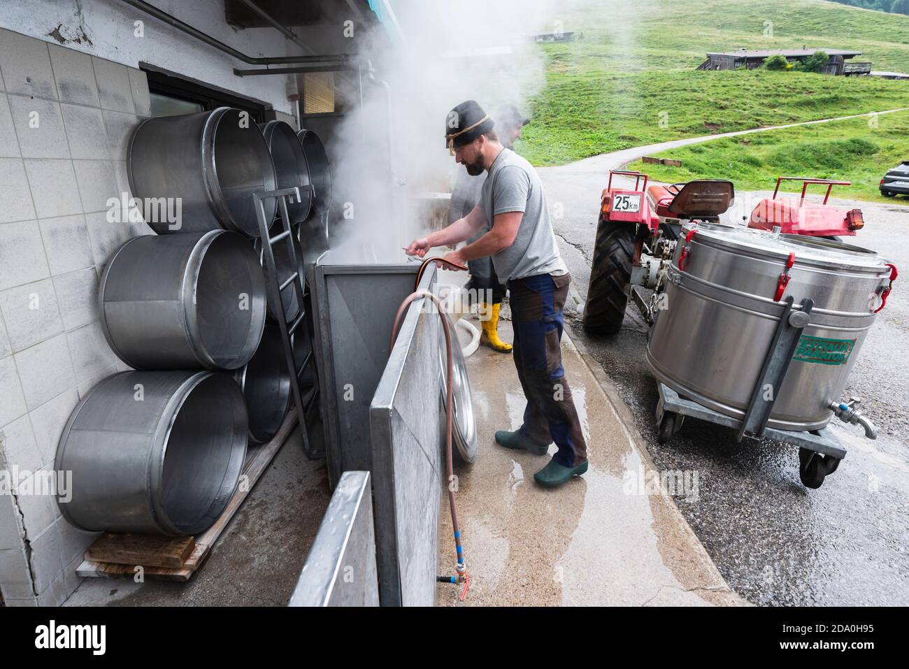 Man cleans the containers for the raw milk with hot, steaming water before the cheese dairy on the Ackernalm, Tyrol, Austria Stock Photo