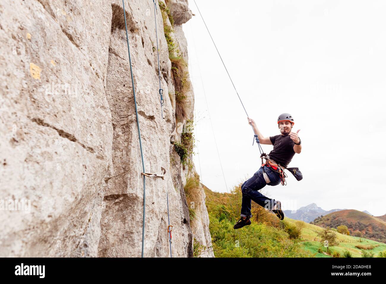 Strong male alpinist in safety equipment climbing on rocky cliff on