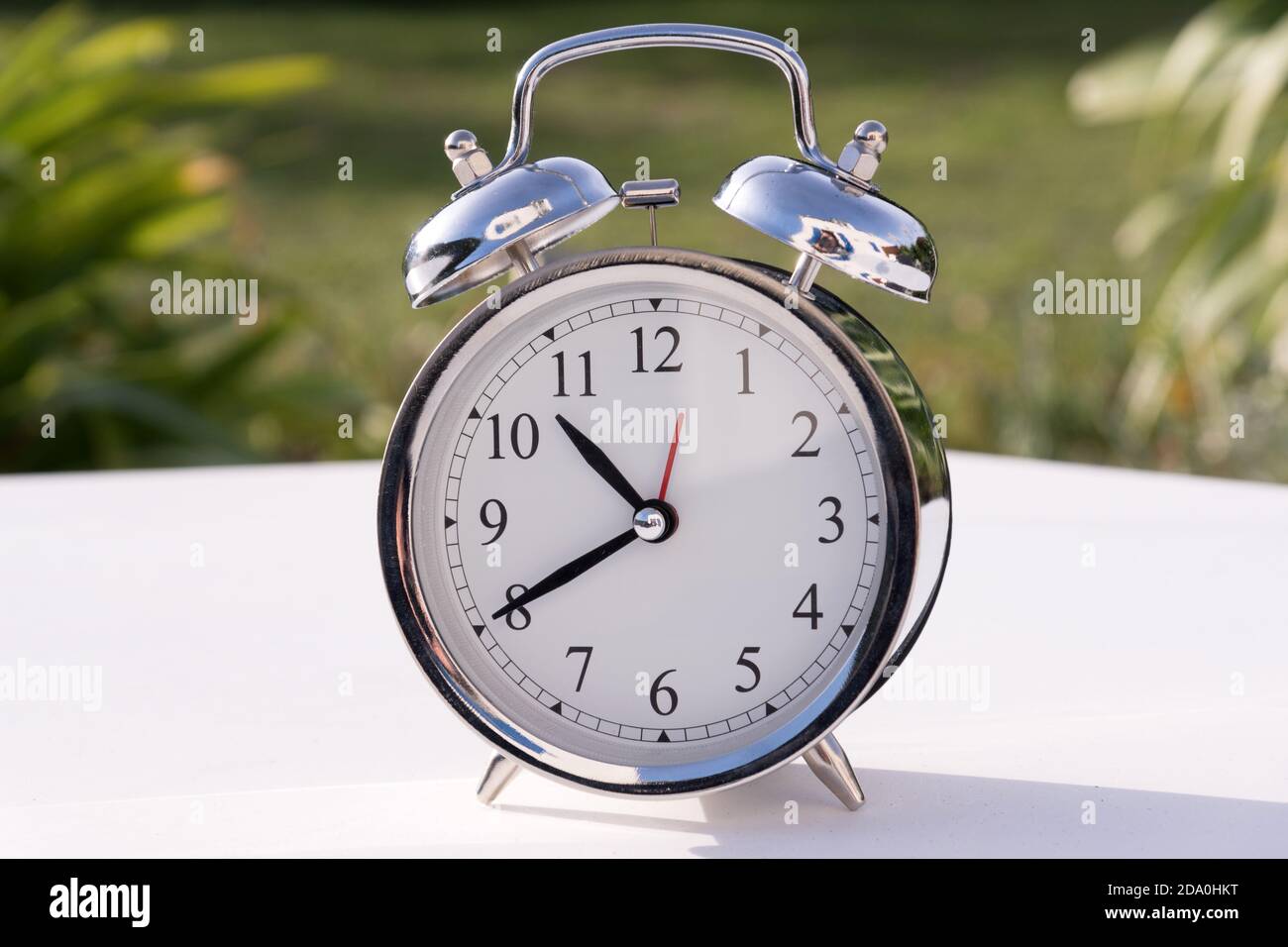 An alarm clock on a garden table Stock Photo