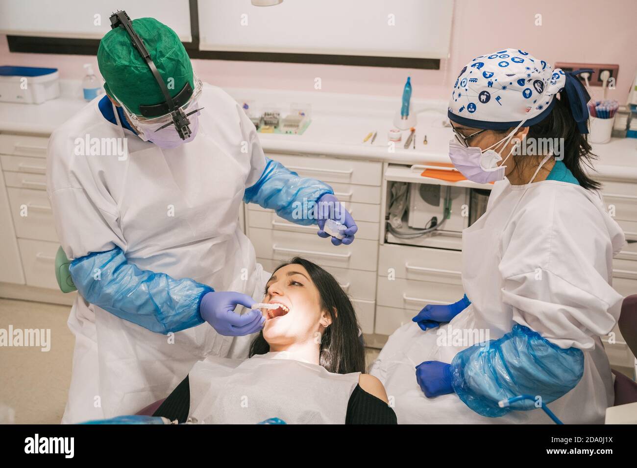 Unrecognizable orthodontist in sterile gloves putting transparent braces on teeth of Woman in clinic Stock Photo