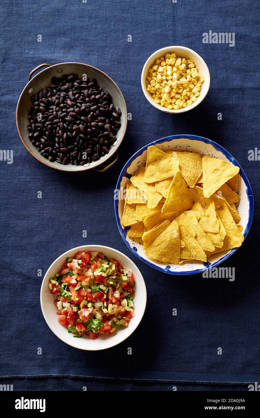 Ingredients for cooking chilaquiles black beans, tortilla chips, corn and salsa Stock Photo
