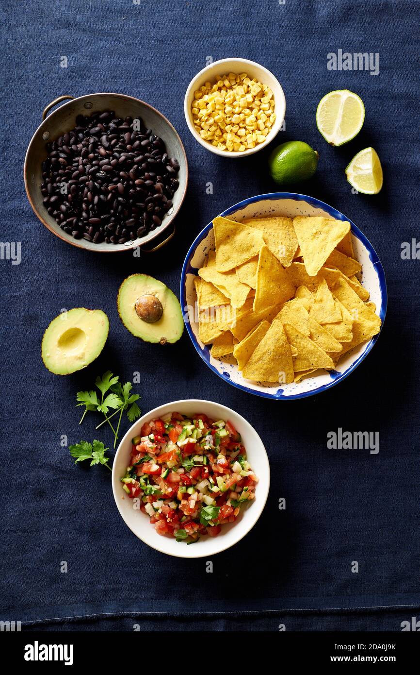 Ingredients for cooking chilaquiles black beans, tortilla chips, corn and salsa Stock Photo