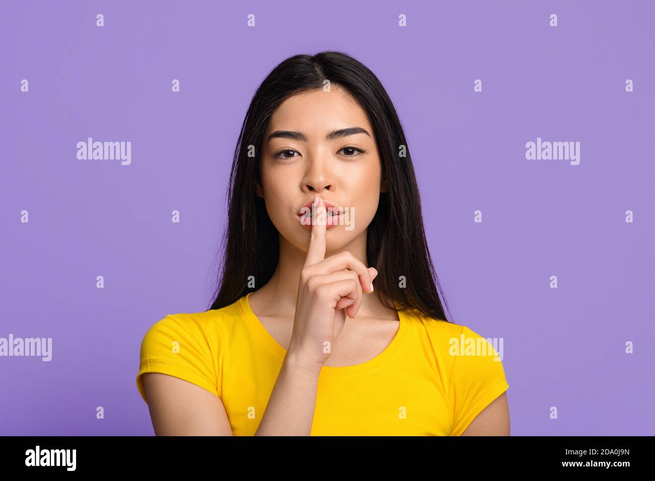 Shhh. Mysterious young asian lady showing keep silence sign at camera Stock Photo