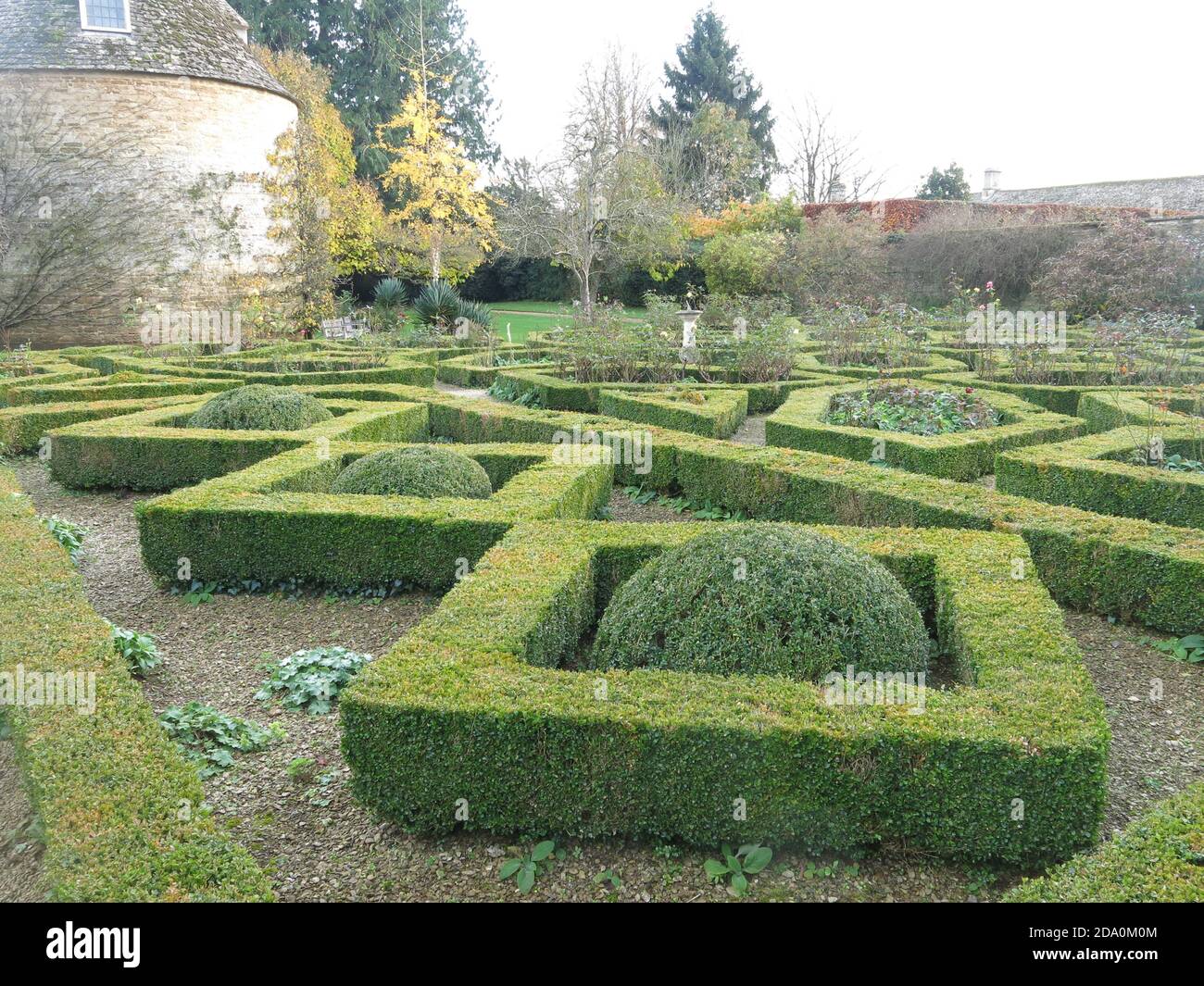 A parterre of box-edged beds surround the old stone Pigeon House in one of the gardens at Rousham House in Oxfordshire, Stock Photo