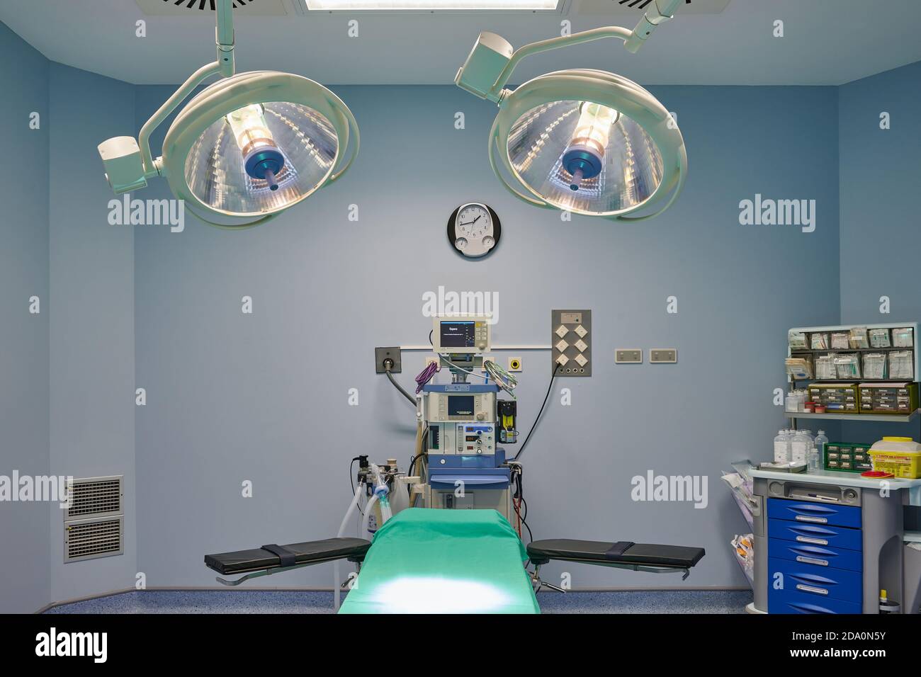 Contemporary operating room interior with couch under shiny lamps near professional devices in
