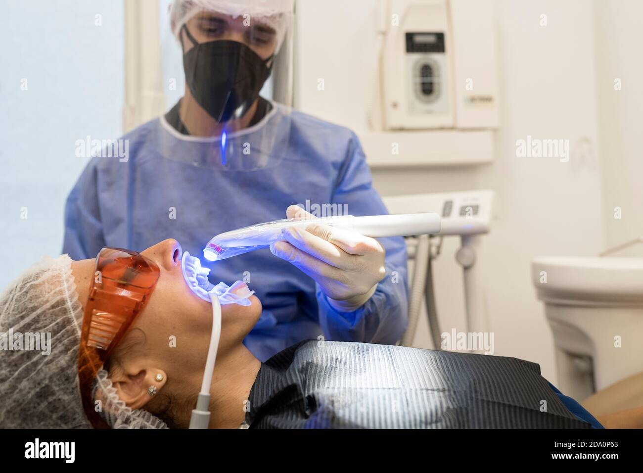 Dentist in gloves using dental ultraviolet curing light tool during
