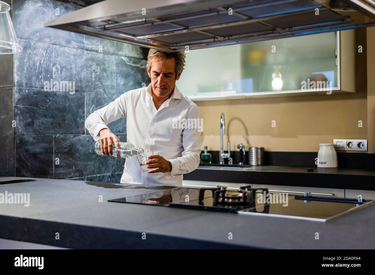 Thoughtful professional chef preparing dish while filling glass with ...