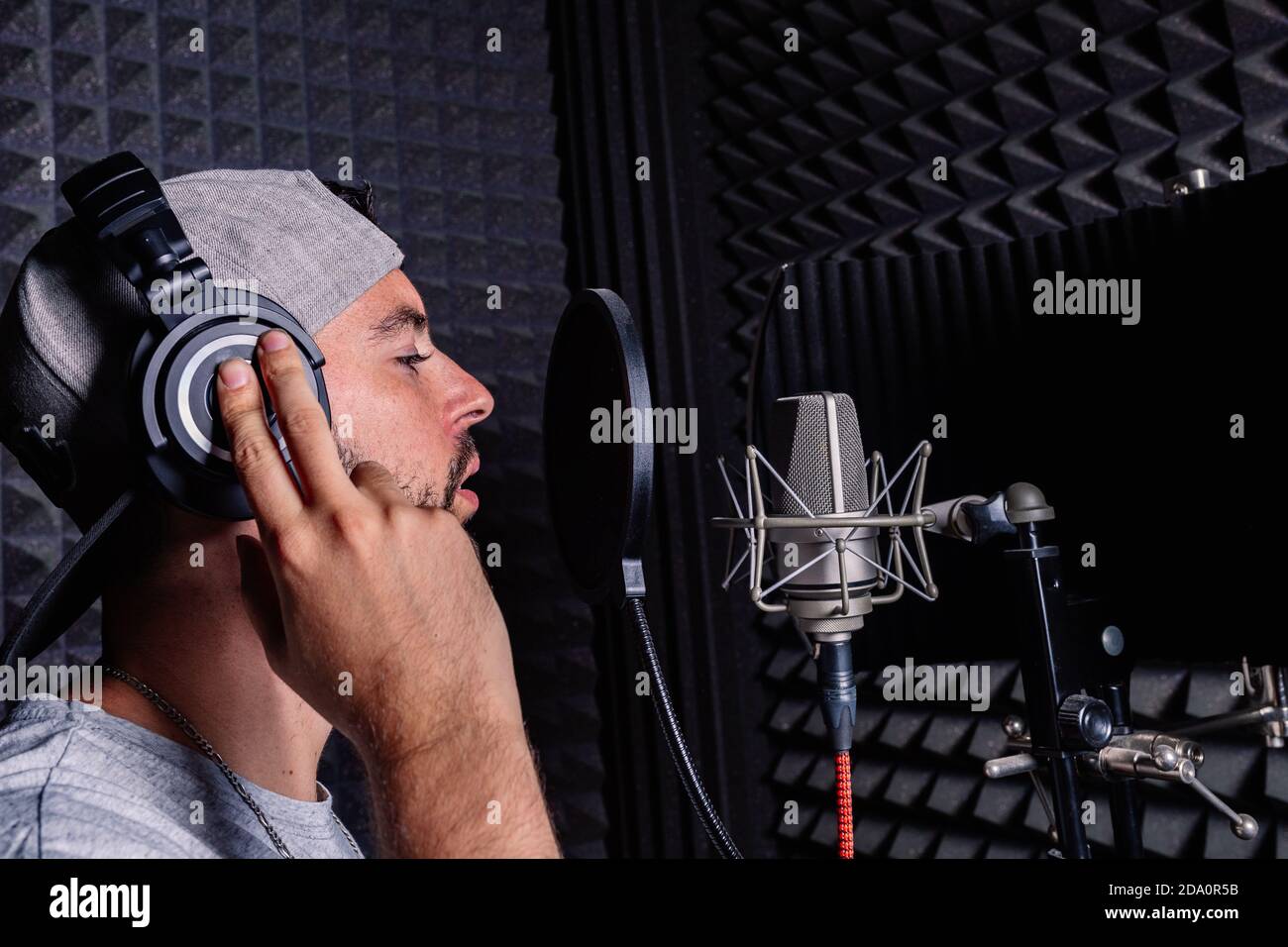 Side view of male singer in headphones and hat standing in acoustic room  with soundproof walls and microphone and recording song in studio Stock  Photo - Alamy