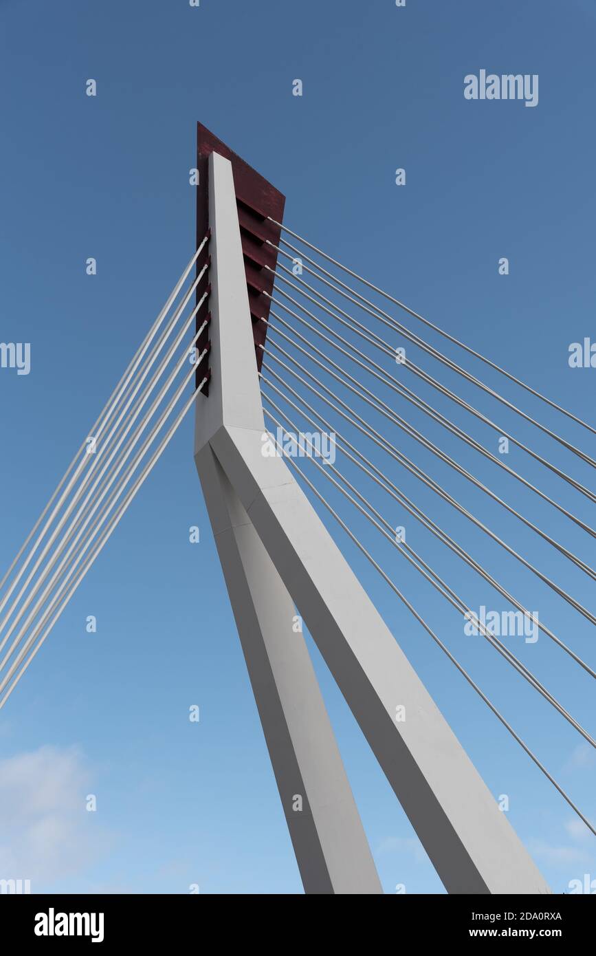 From below of white contemporary suspension bridge with high column connecting many cables together against blue sky Stock Photo