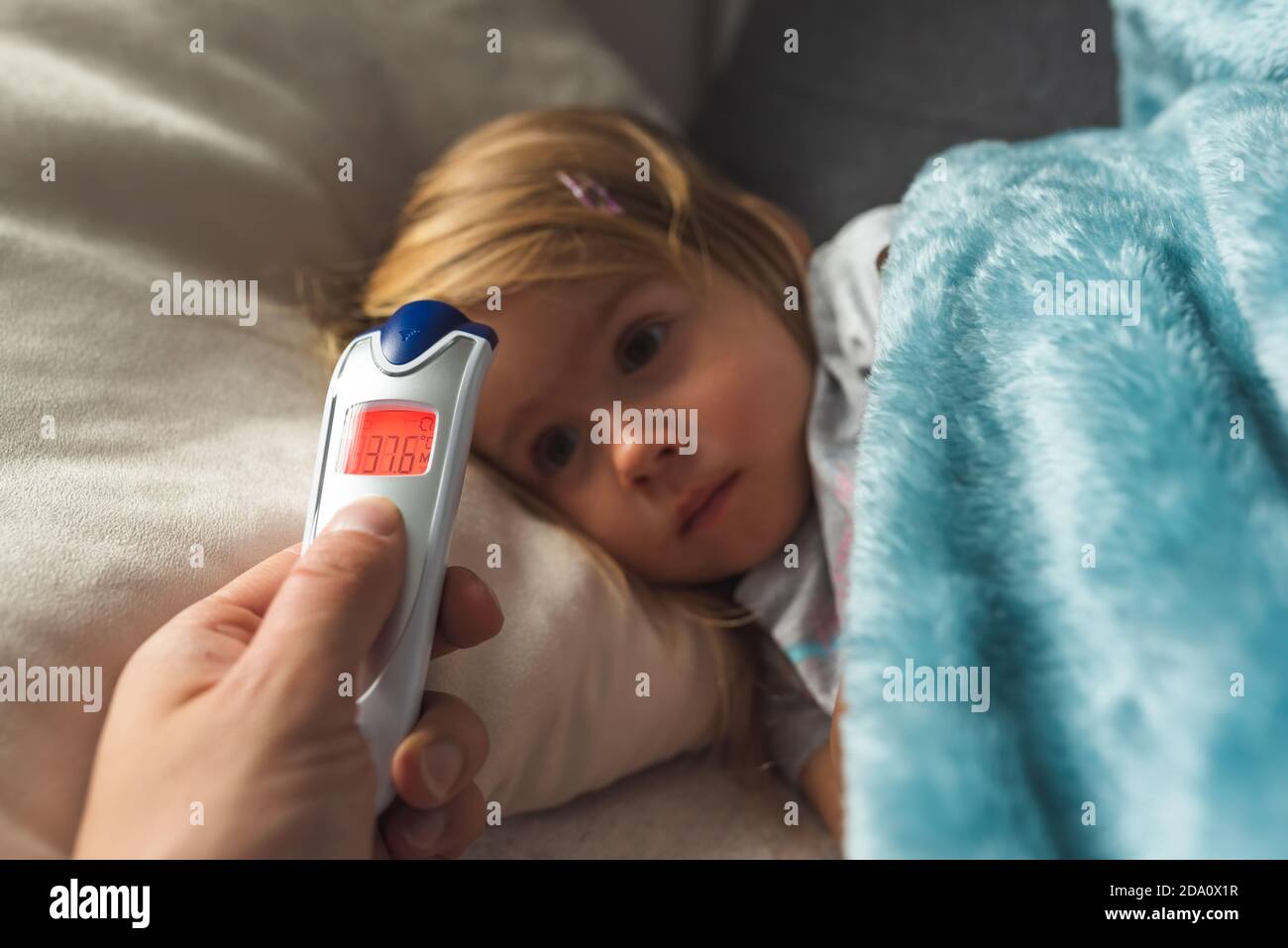 Parent takes temperature for her child with infrared thermometer at
