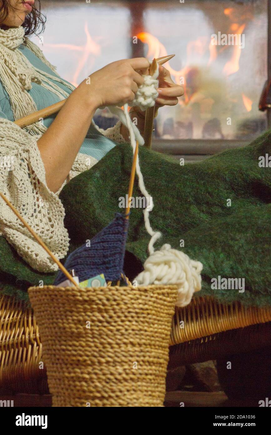 Side view of a woman sat on a rattan chair knitting Stock Photo - Alamy