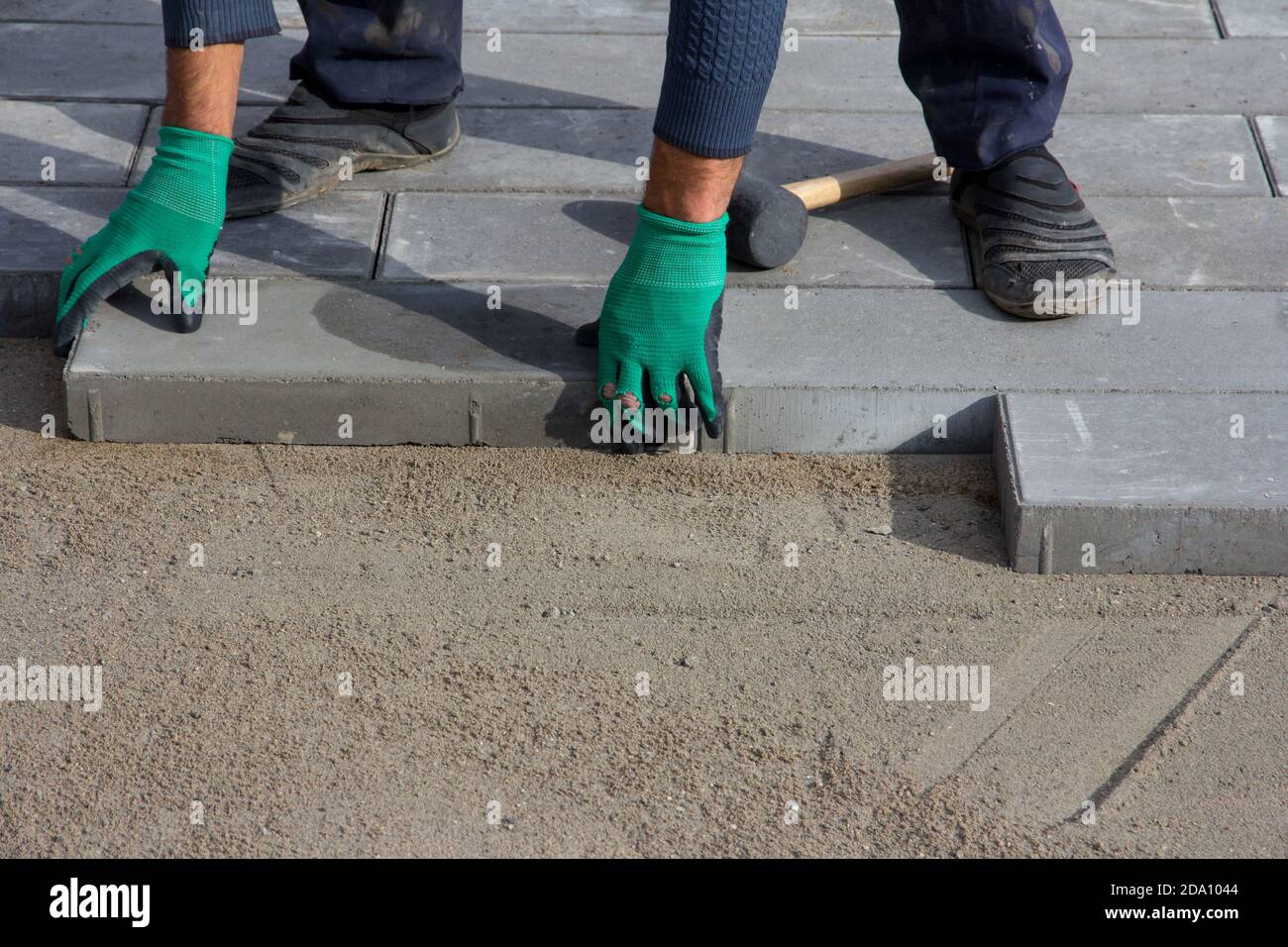 Brick Paver Working. Worker lay paving tiles, construction of brick pavement. Architecture background Stock Photo