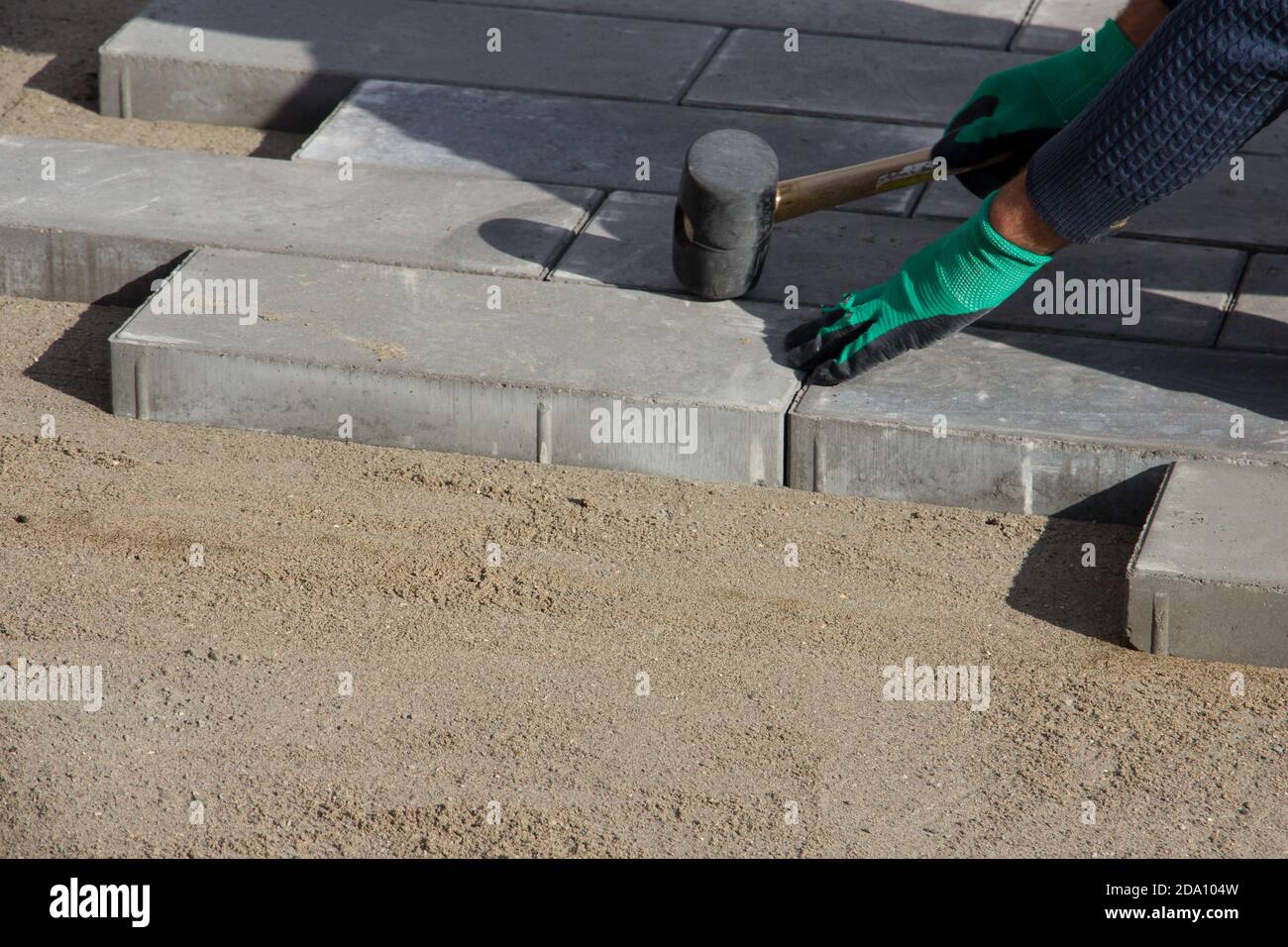 Brick Paver Working. Worker lay paving tiles, construction of brick pavement. Architecture background Stock Photo