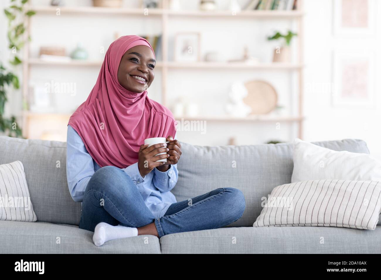 Home Rest. Dreamy Smiling Black Muslim Woman Relaxing On Couch With ...