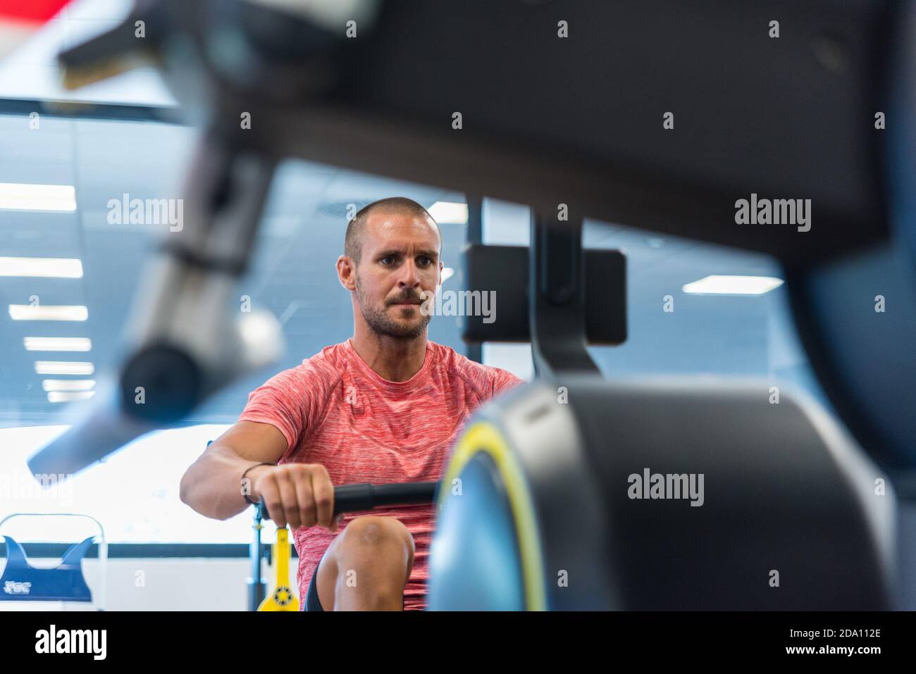 Concentrated athletic male doing exercises on rowing machine while ...