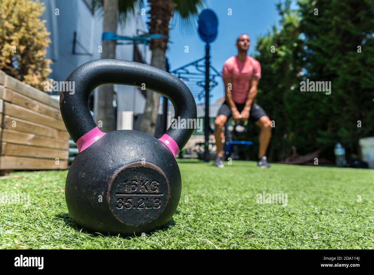 Ground level of heavy kettlebell placed on lawn on blurred background of  strong male athlete doing swings with metal equipment during dynamic  training Stock Photo - Alamy