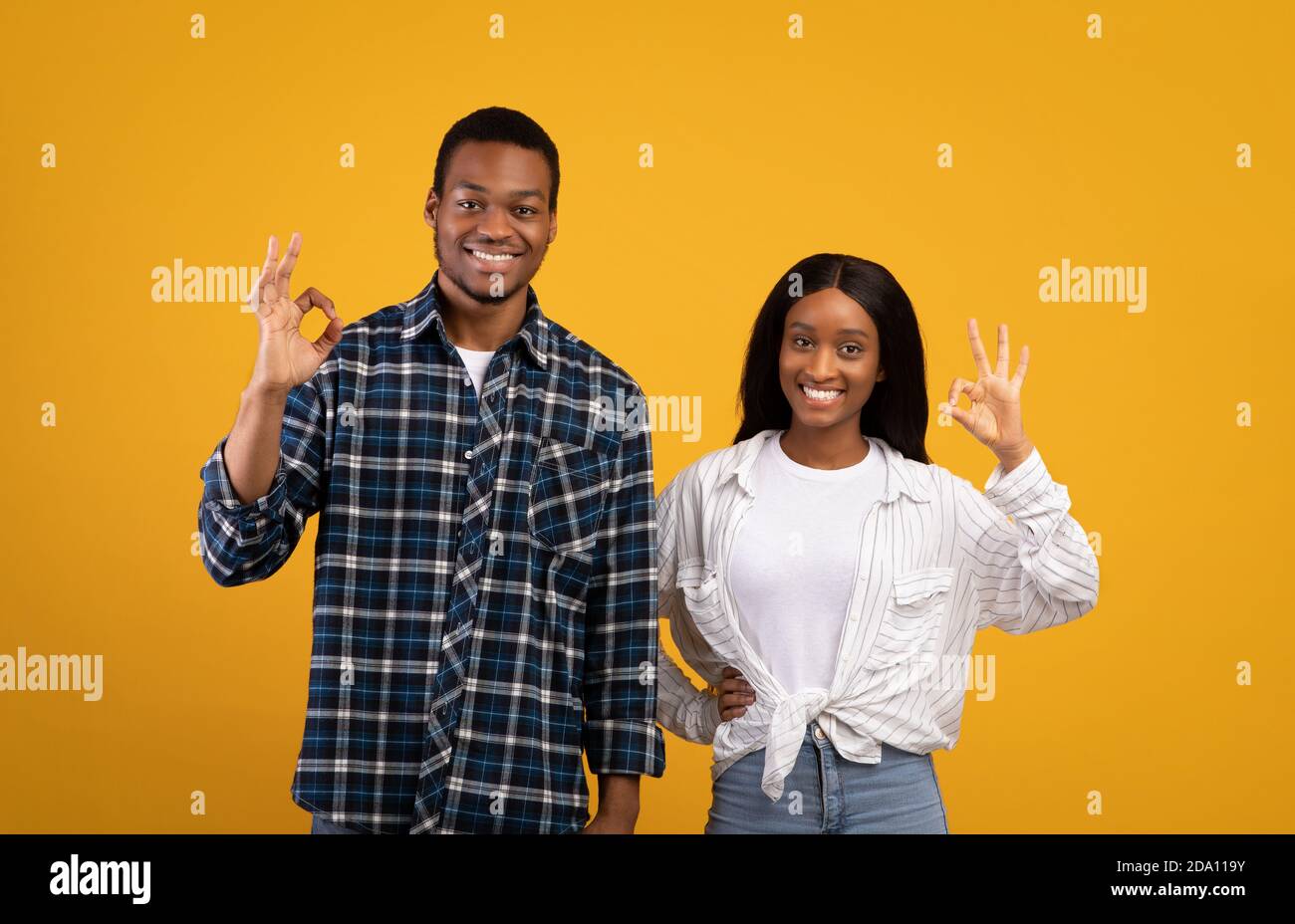 Happy millennial african american man and woman in casual, show OK with hands and look at camera Stock Photo