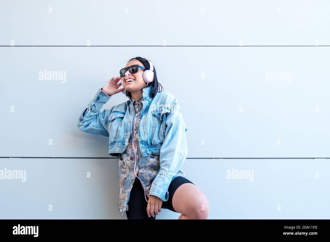 Hispanic female listening to music with headphones leaned against the ...