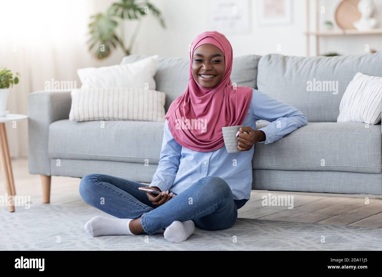 Smiling Black Islamic Woman Relaxing On Floor With Smartphone And ...