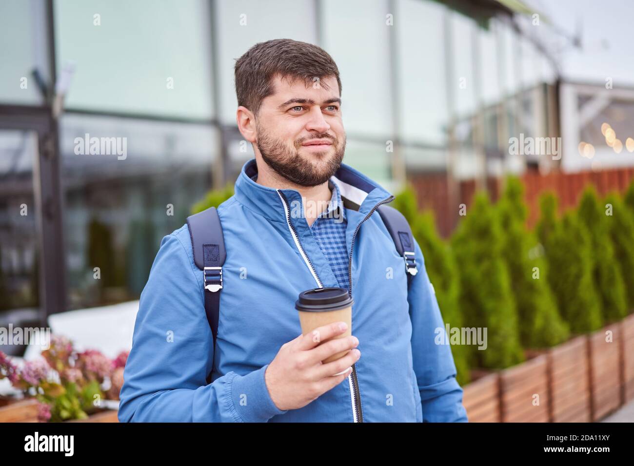 Bearded man drinks coffee from paper cup outdoors. Stock Photo