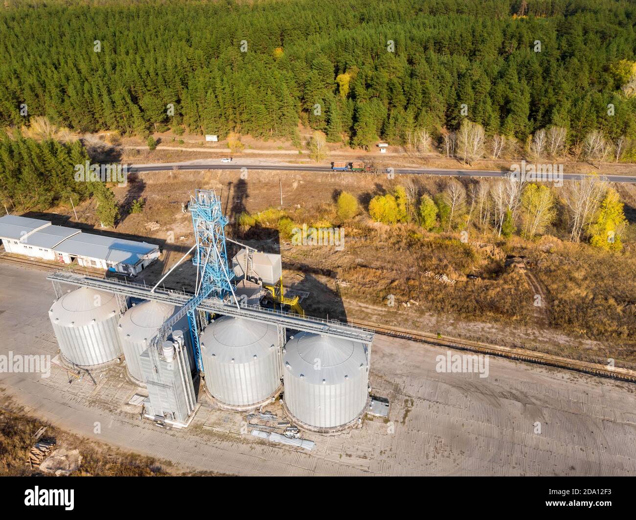 Aerial drone view modern steel agricultural grain granary silos cereal storage warehouse loading cargo grain carrier sunset. Agribuisness farmland Stock Photo