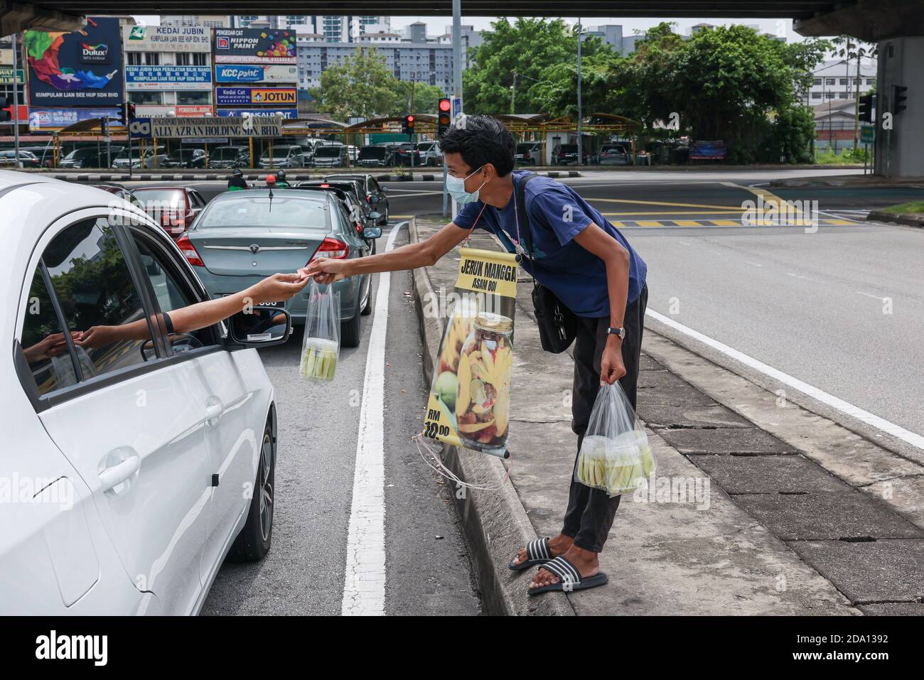 Kuala Lumpur, Malaysia. 08th Nov, 2020. A young man wearing a face mask with a sign hanging around his neck is seen receiving payment after selling fruits on the road.The government of Malaysia has implemented an extension of the Conditional Movement Control Order (CMCO) from November 9 to December 6 2020, in most states as Covid-19 cases raise in the nation. Credit: SOPA Images Limited/Alamy Live News Stock Photo