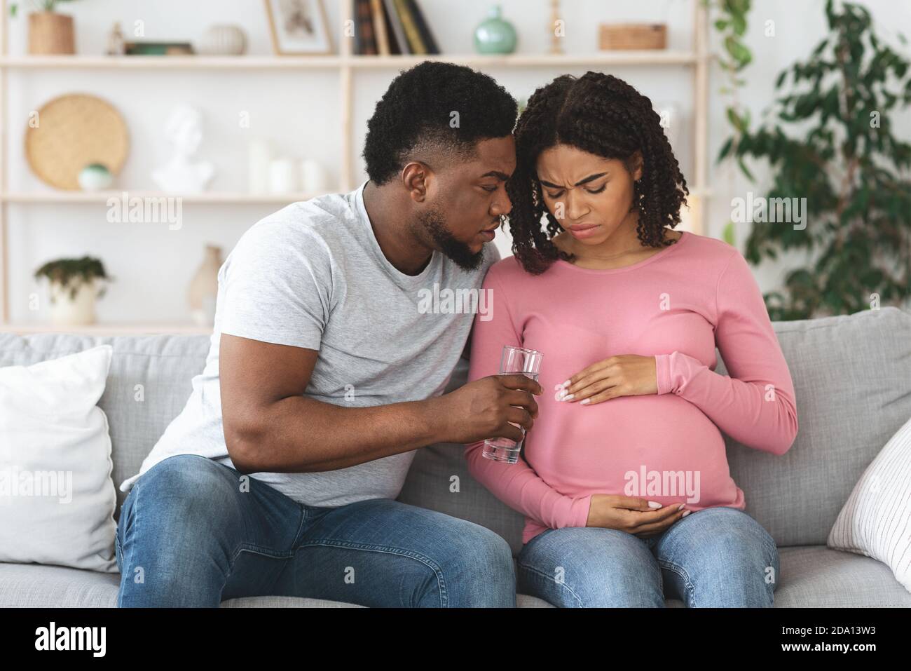 Black pregnant wife feeling sick, husband giving glass of water Stock Photo Alamy