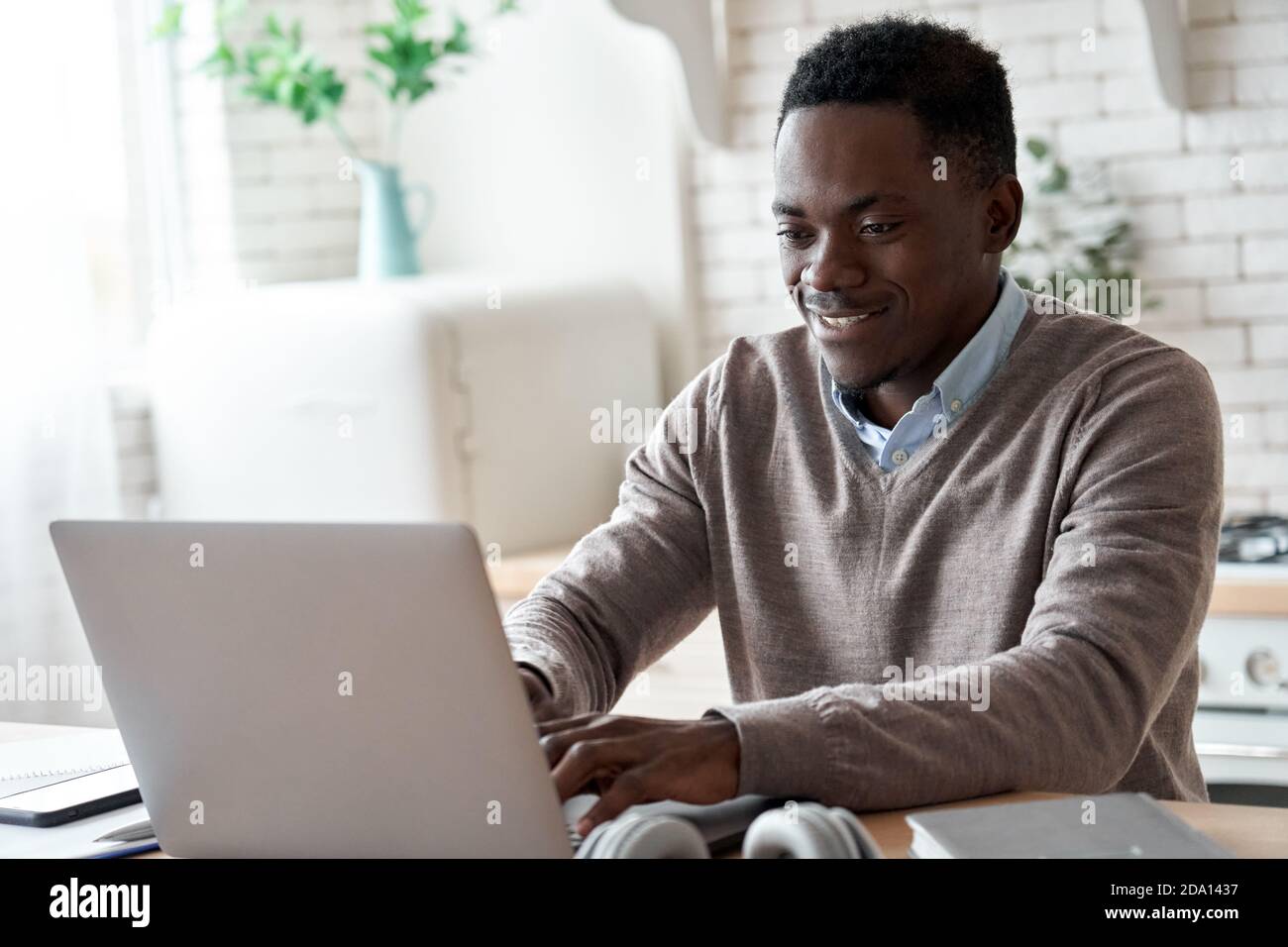Smiling african american man using laptop computer working from home office. Stock Photo