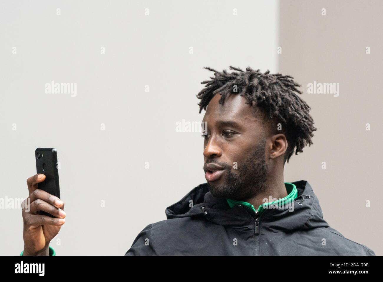young man with dreadlocks holding smartphone during street protest Manchester 08-11-2020, anti lockdown protest lockdown2 covid covid19 Stock Photo