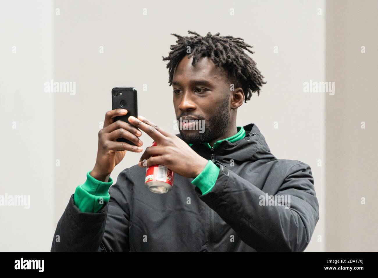young man with dreadlocks holding smartphone during street protest Manchester 08-11-2020, anti lockdown protest lockdown2 covid covid19 Stock Photo