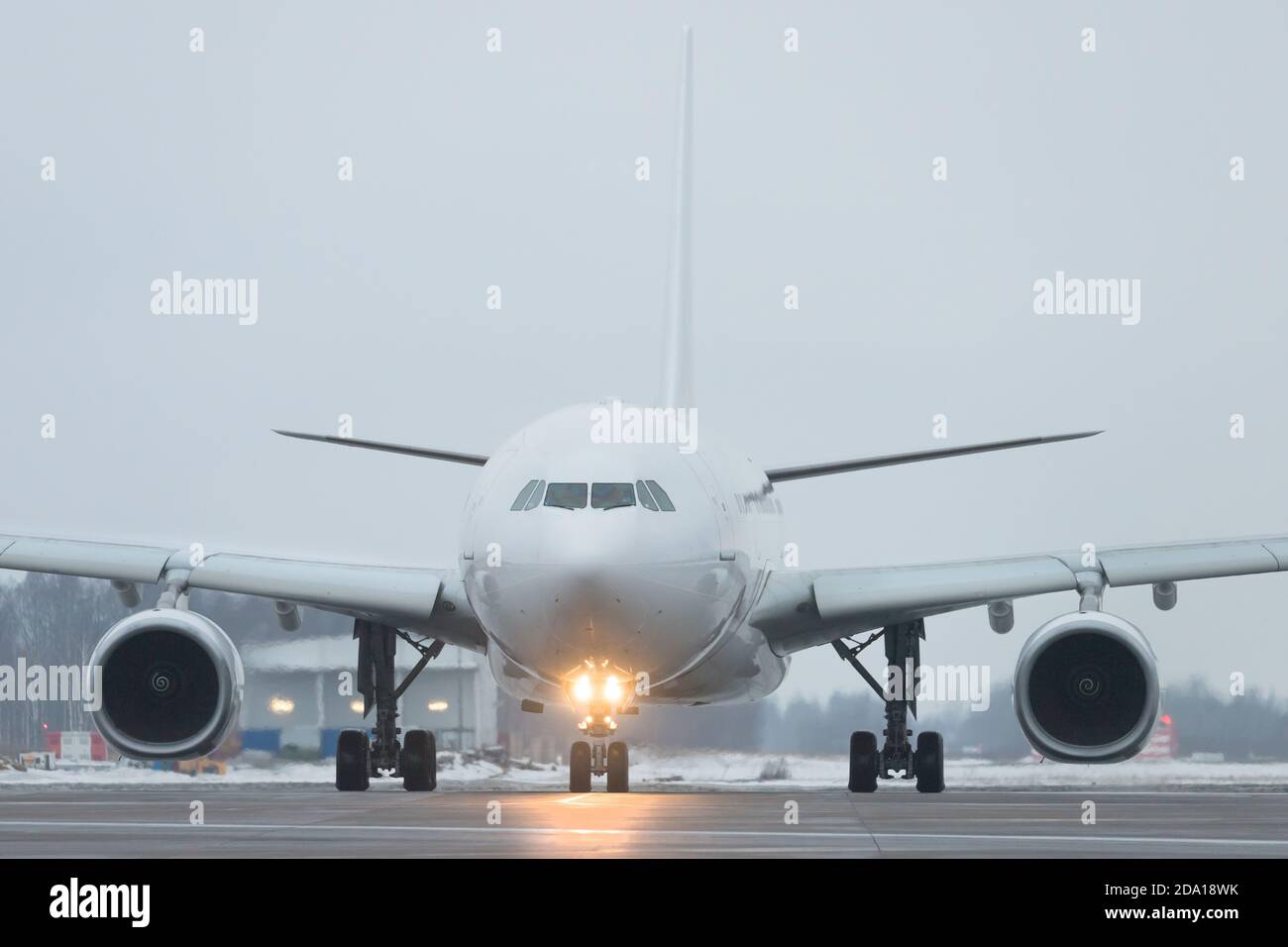 Closeup of passenger wide-body plane rides after landing in twilight, front view, winter time. Included landing lights at the aircraft. Aviation conce Stock Photo