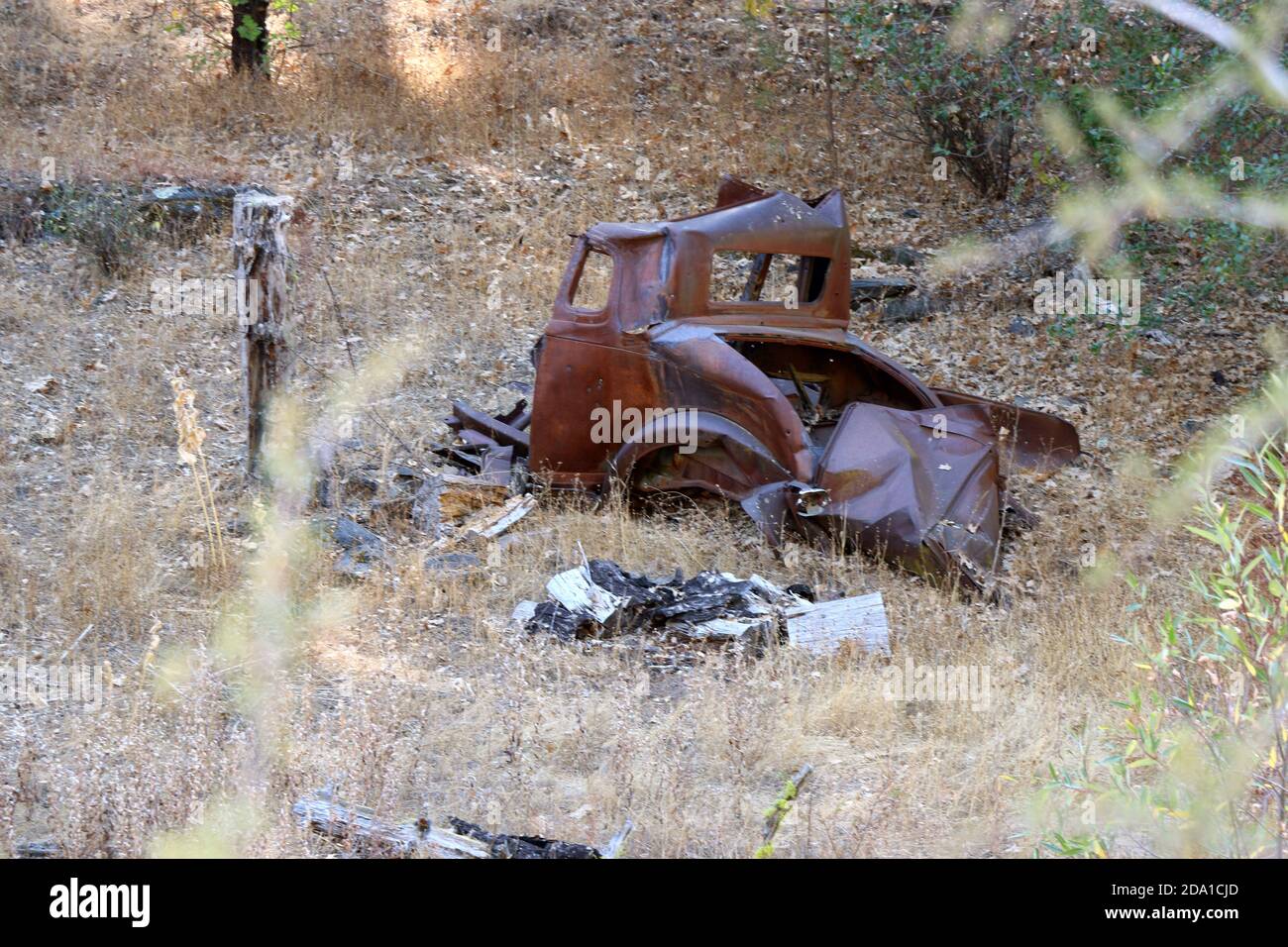 Rusted brown truck lies in an open field, Pine Mountain Lake CA. Stock Photo