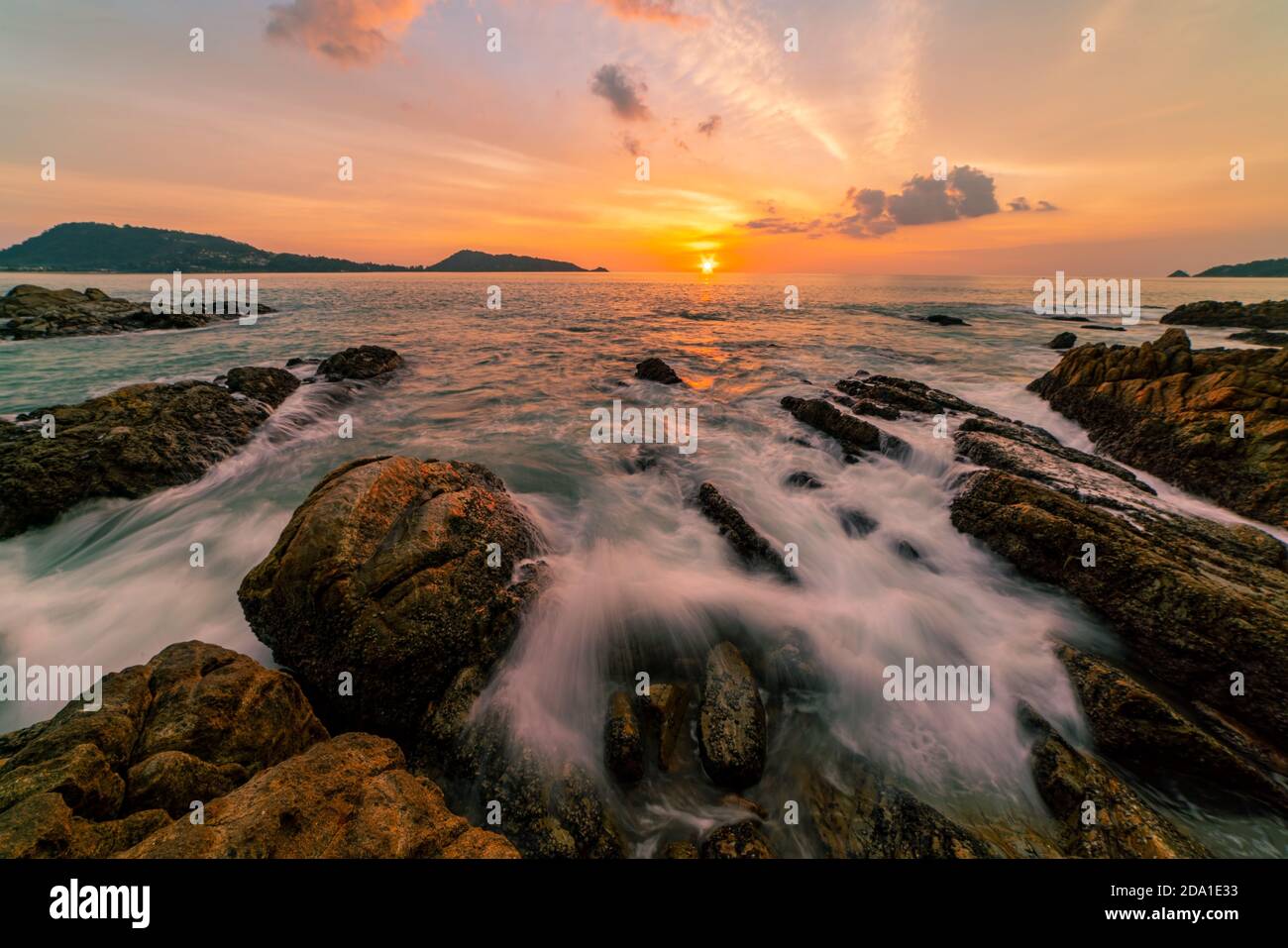 Long exposure image of Dramatic sky seascape with rocks in the foreground sunset or sunrise over sea scenery background Stock Photo