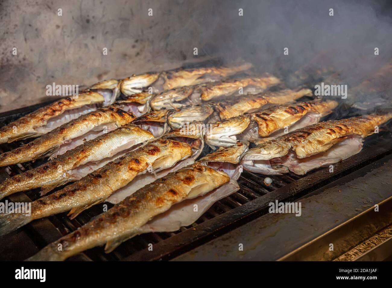 Grilled sea bass fish closeup. In process. European seabass, chef is