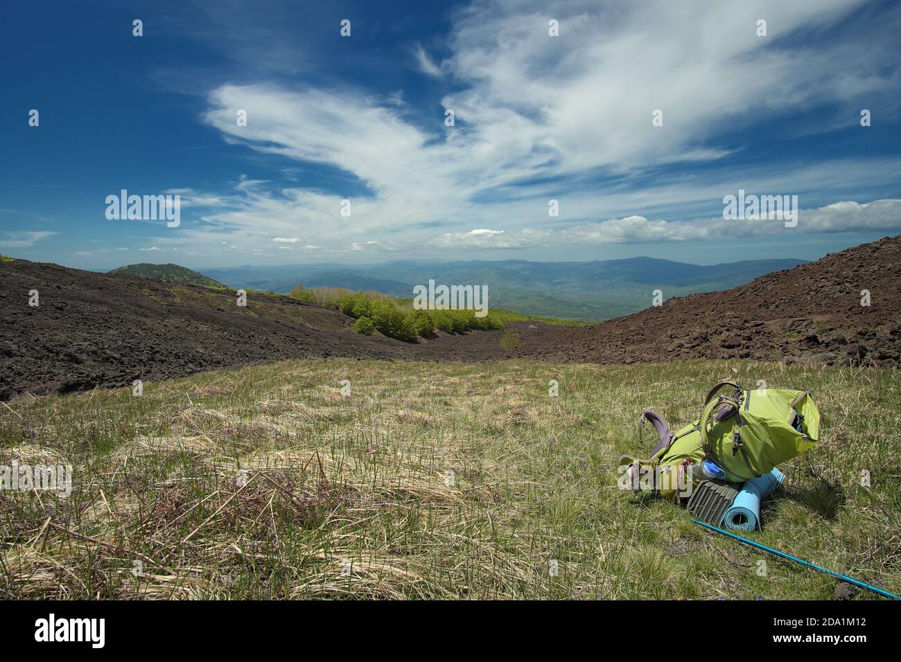 green backpack in mountain landscape of Etna Park, Sicily Stock Photo