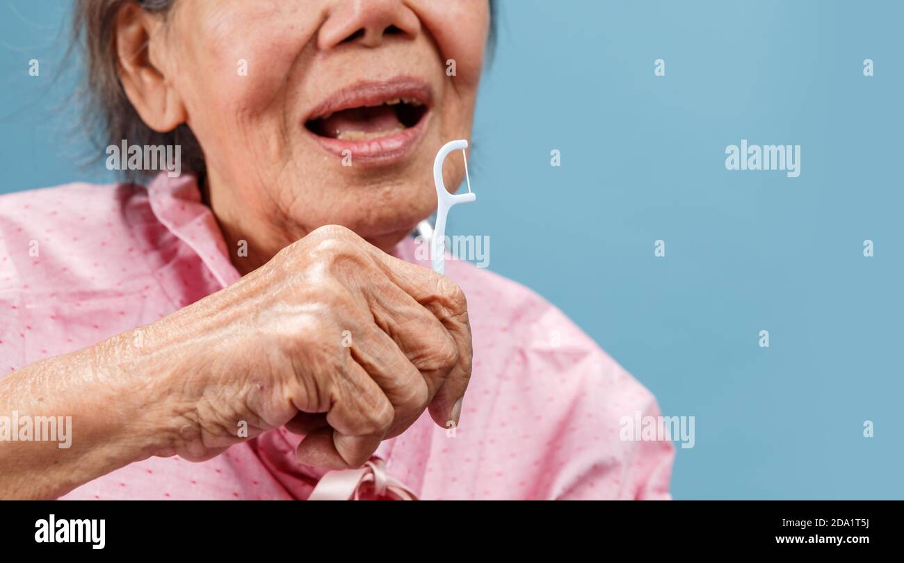 Caregiver take care asian elderly woman while using dental fross stick. Stock Photo