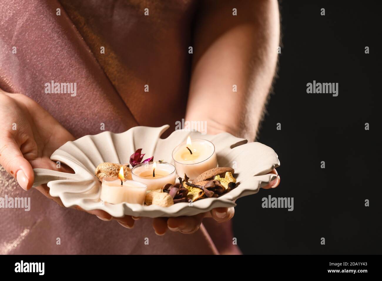 Woman holding tray with burning candles for celebration of Divaly on dark background, closeup Stock Photo