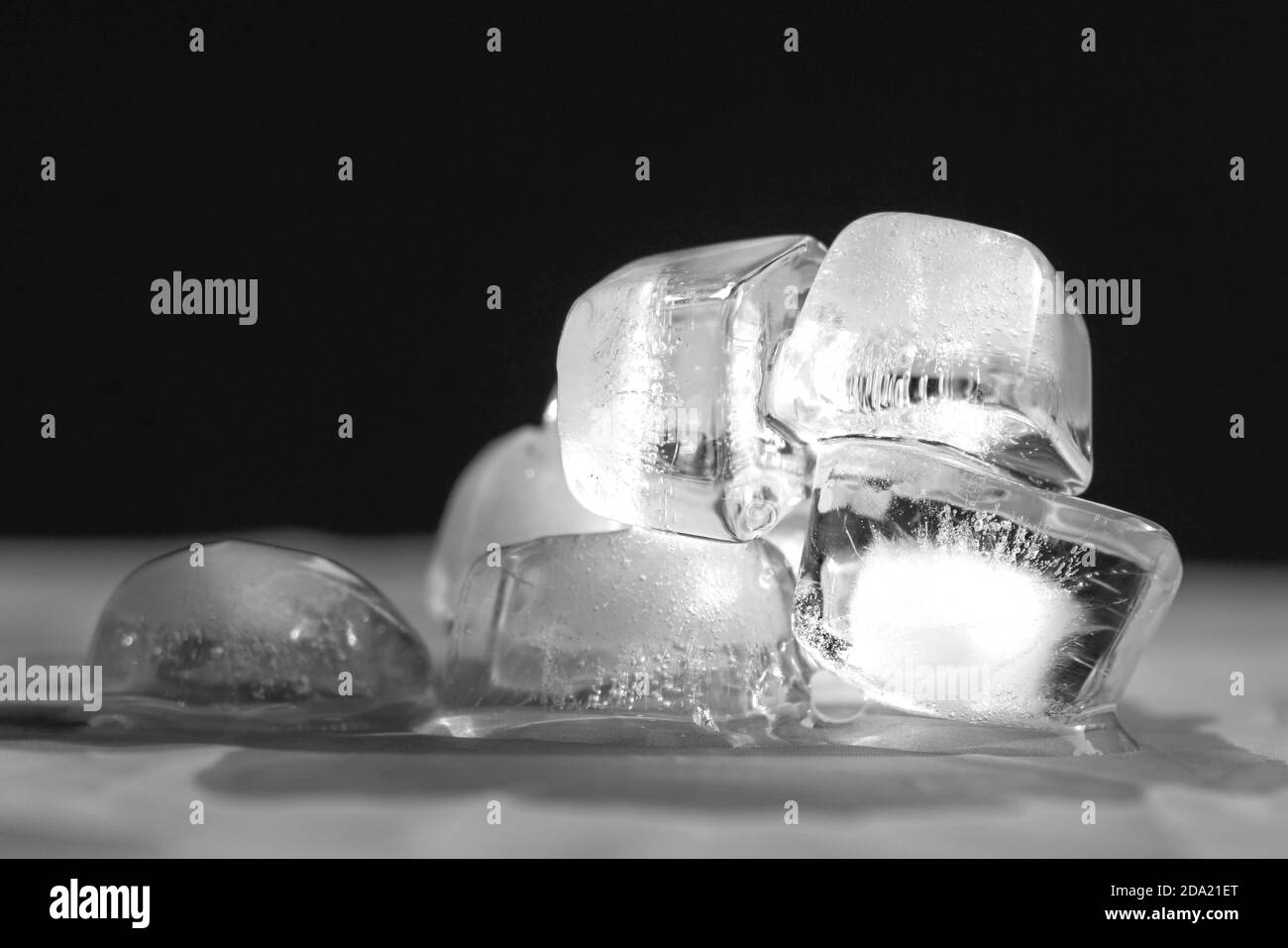 Melting ice cubes on top of table. Black background. Stock Photo