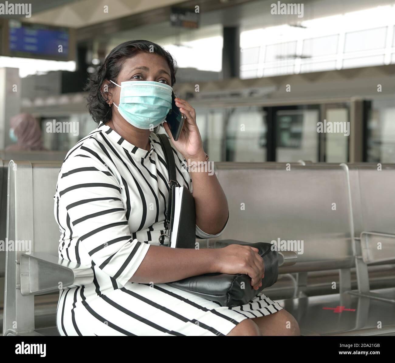 Portrait of woman wearing face mask sitting and talking on the cellphone at subway station.. Stock Photo