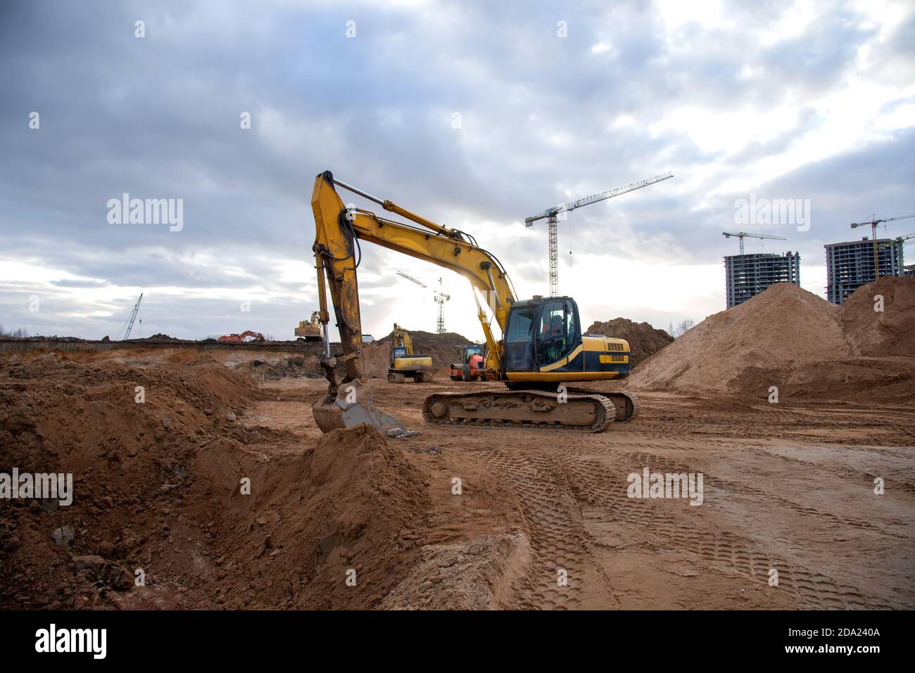 Excavator during earthmoving at construction site. Backhoe dig ground ...