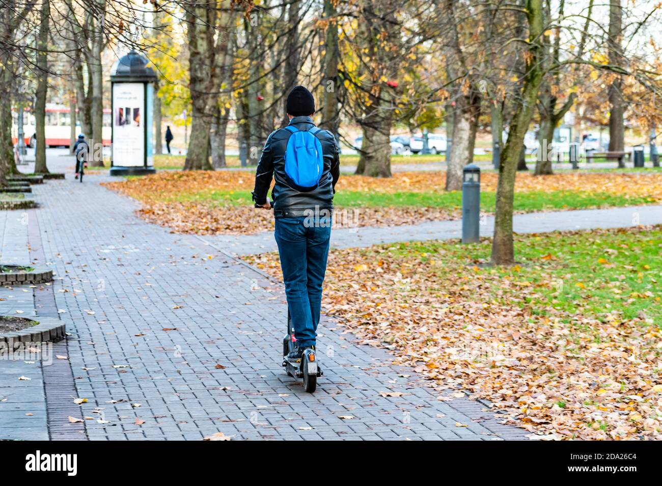 Boy with electric scooter and backpack. Sustainable transport. Road bike with trees and autumn background Stock Photo
