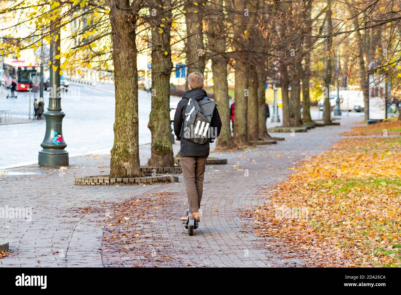 Boy with electric scooter and backpack. Sustainable transport. Road bike with trees and autumn background Stock Photo