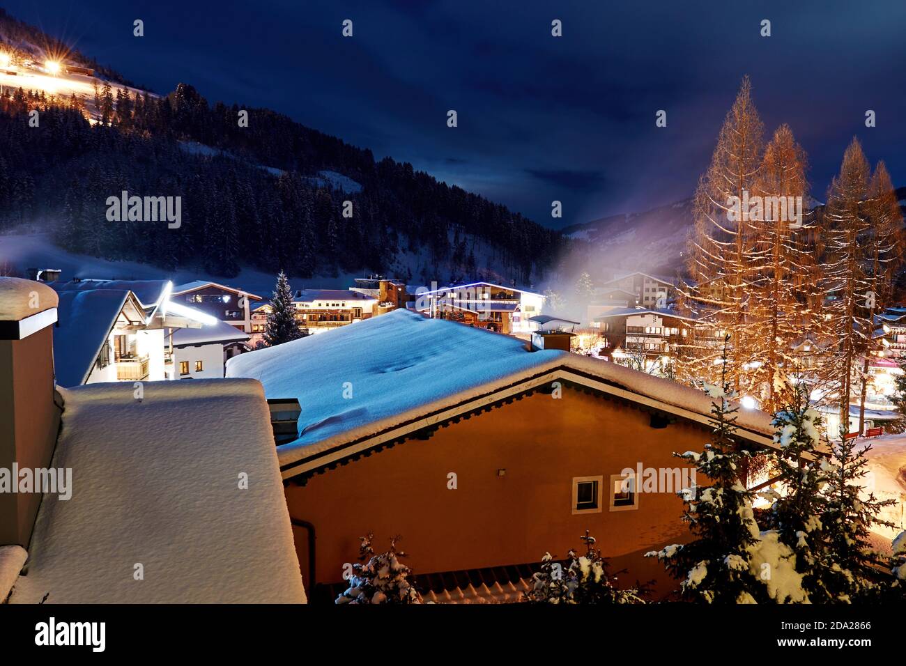 Winter Alpine village on the snowy mountain slope illuminated by street