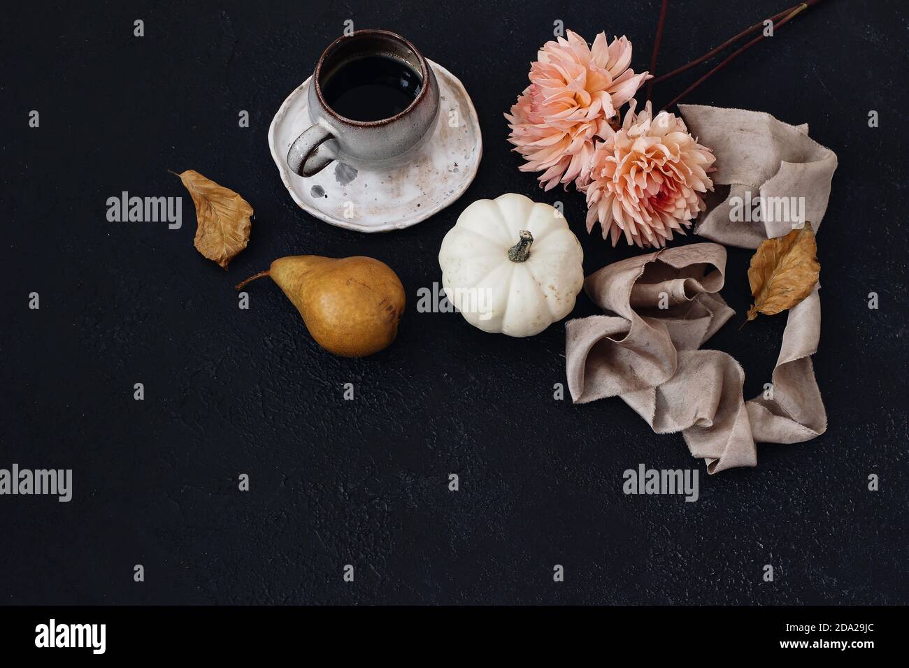 Autumn still life composition. Cup of coffee, pear fruit and white pumpkins with pink dahlia flowers. Black table background. Beech leaves. Moody fall Stock Photo