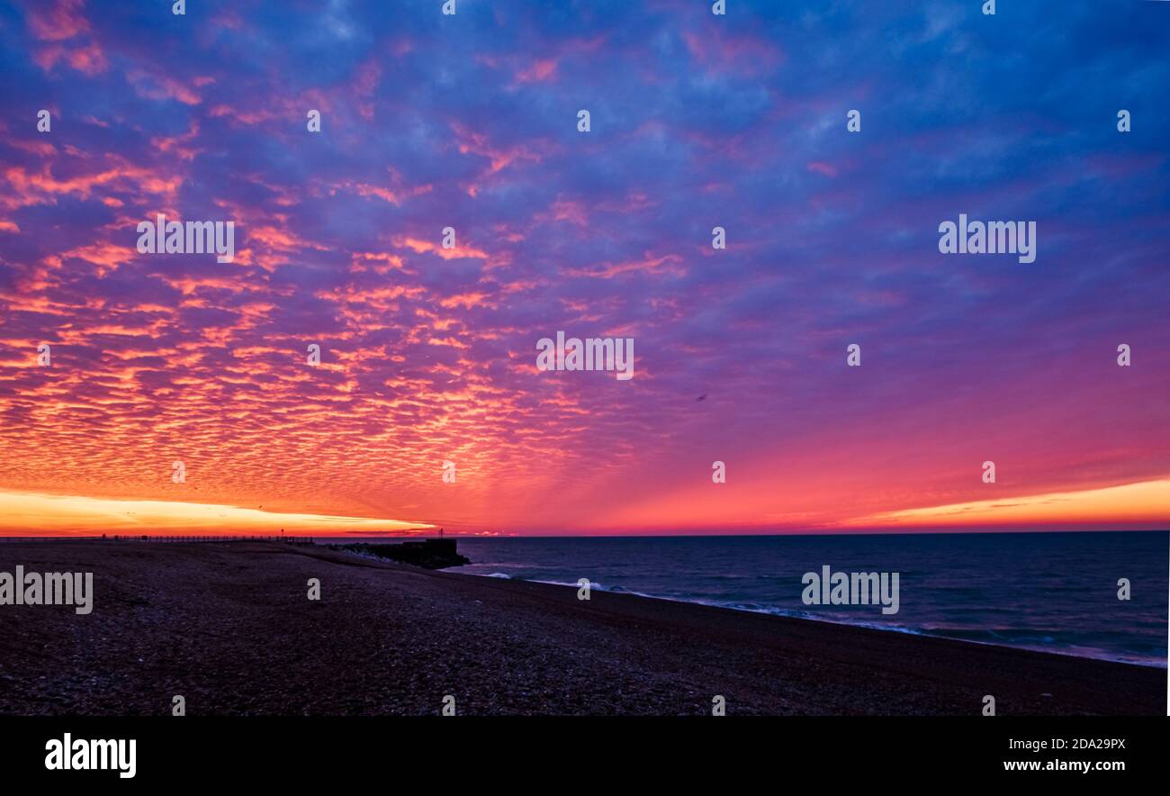 Dramatic red dawn mackerel sky over the beachfront of Hastings in east Sussex south east England Stock Photo