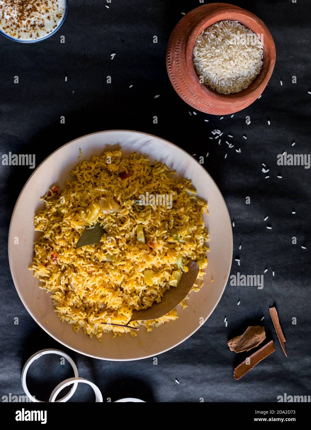 Spicy Rice Background Cooked spicy rice on a plate with some of the ingredients on a black ...