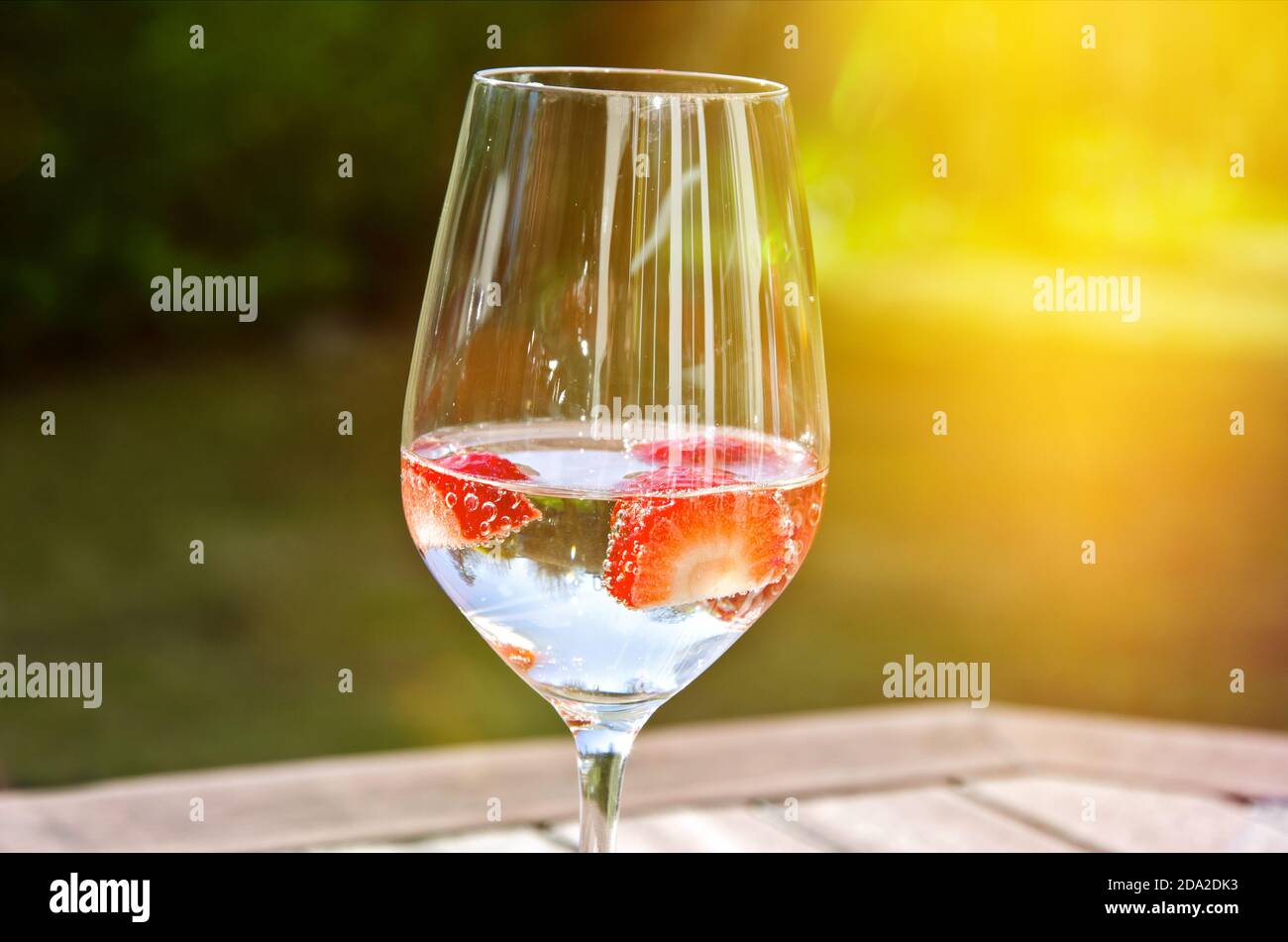 Glass of fresh sparkling wine with strawberries in the garden on a sunny day Stock Photo
